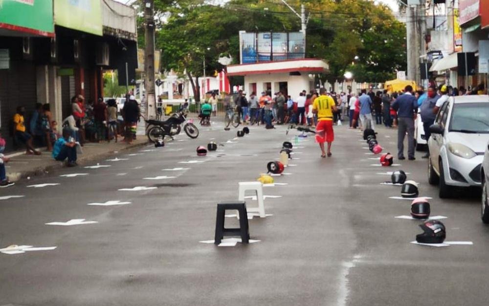 Moradores usam capacetes e bancos plásticos para marcar lugar em fila de agência